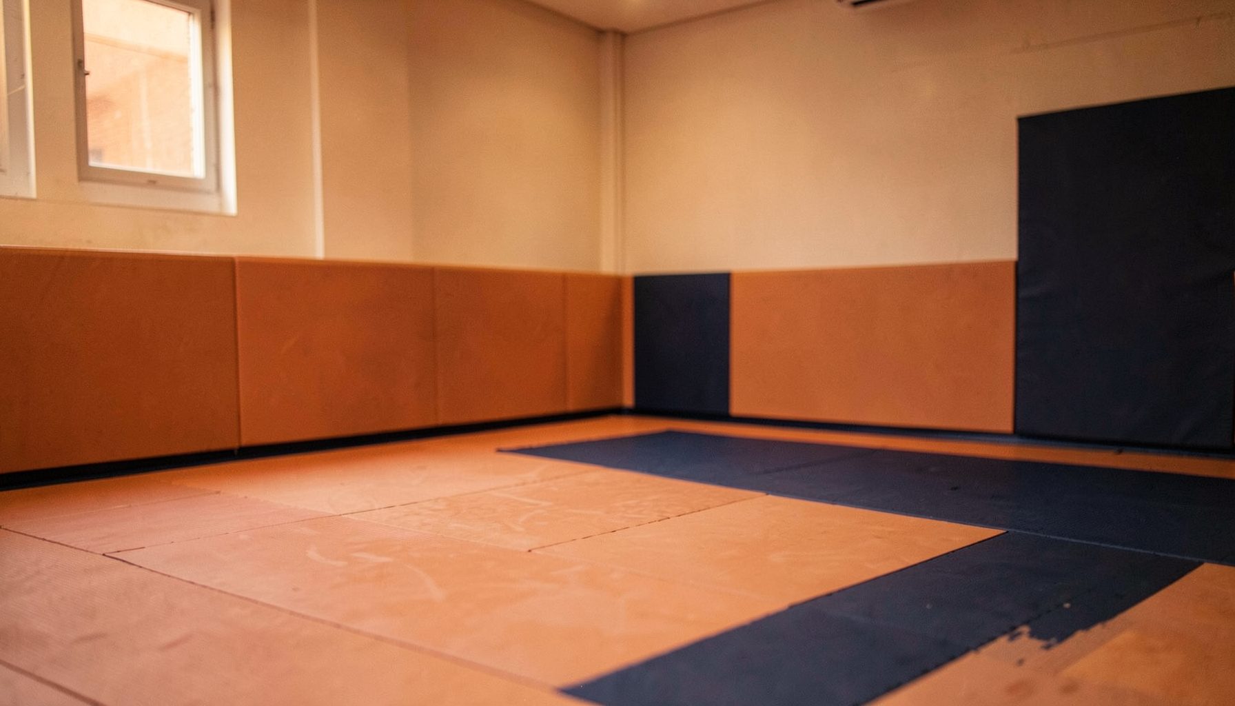 A warm, softly lit indoor space with a padded floor, muted orange and deep navy accents, conveying gentle energy and focus